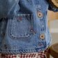 Light blue denim jacket close-up with chest pocket, button placket, embroidered motifs