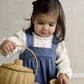 Blue denim pinafore dress over white heart-print bodysuit, holding a wicker basket