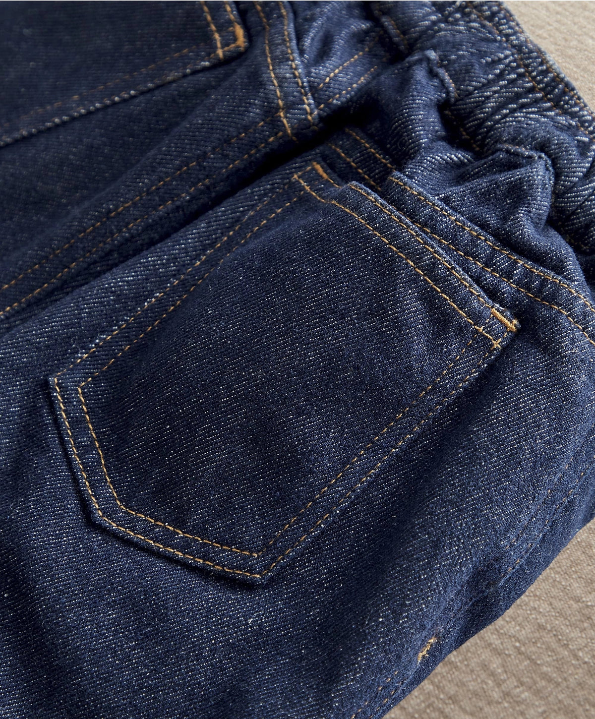 Dark blue denim jeans close-up of stitched front pocket and seams