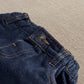 Dark blue denim jeans close-up of waistband button and side pocket