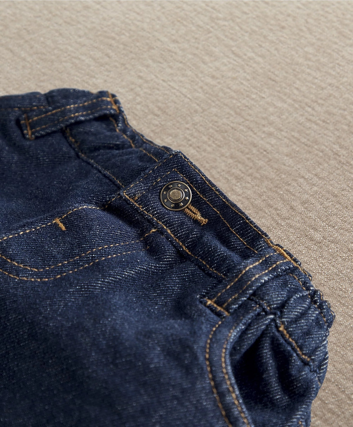 Dark blue denim jeans close-up of waistband button and side pocket