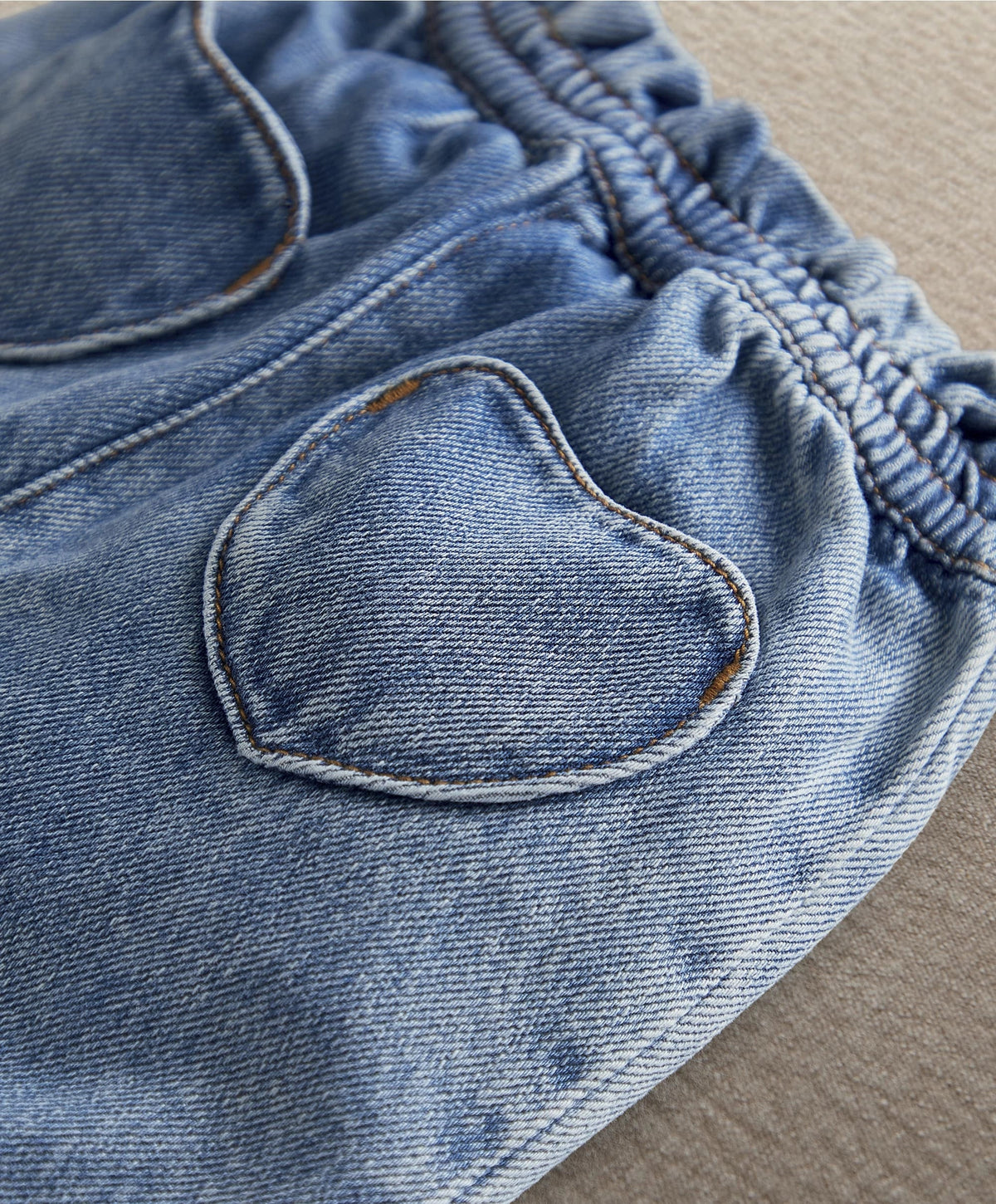Heart-shaped pocket on denim shorts with elastic waistband and topstitching