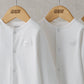 White sleepsuits close-up with snap-button front and small chest logo, pack of three