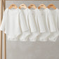White long-sleeve bodysuit 5-pack on hangers, round neck and snap crotch