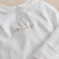 White baby romper with long sleeves and embroidered "born in 2027" logo