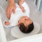 Textured round baby pillow supporting an infant, with neck cutout
