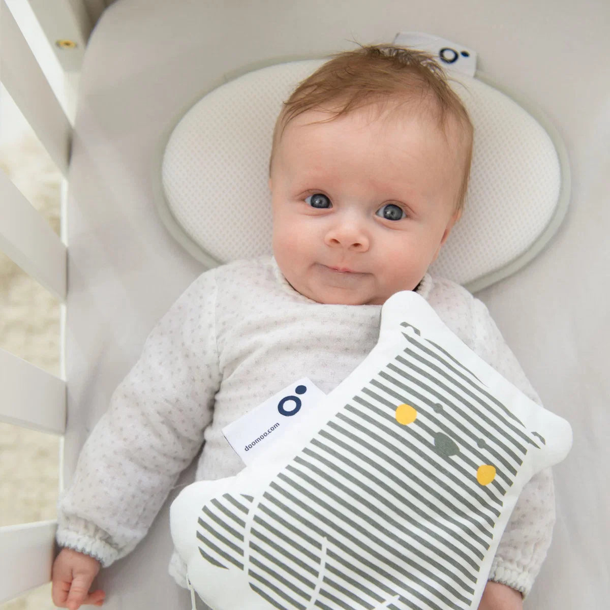 Textured oval baby pillow supporting a baby, with neck cutout