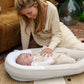 Sand beige baby cocoon nest holding a newborn, with white inner liner