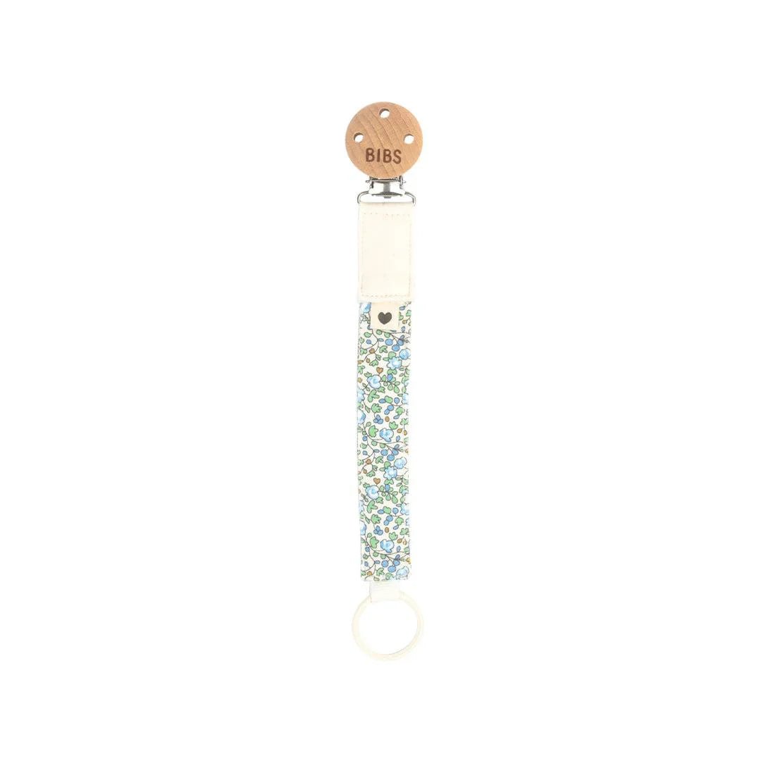 Ivory floral pacifier clip with round metal ring.
