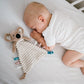 Koala cuddly flat toy near a baby's cheek, striped cream body