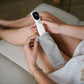 Non-contact infrared thermometer held near skin on forearm, white body and black head
