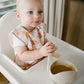 Kids’ apron in light pink with farm-pattern print, worn at chest