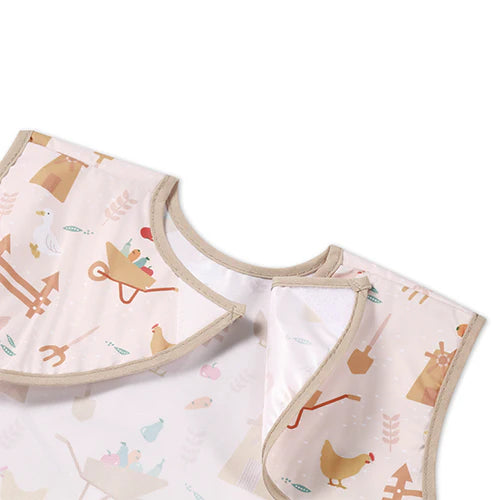Light pink sleeveless farmer apron with neck bib and farm scene pattern