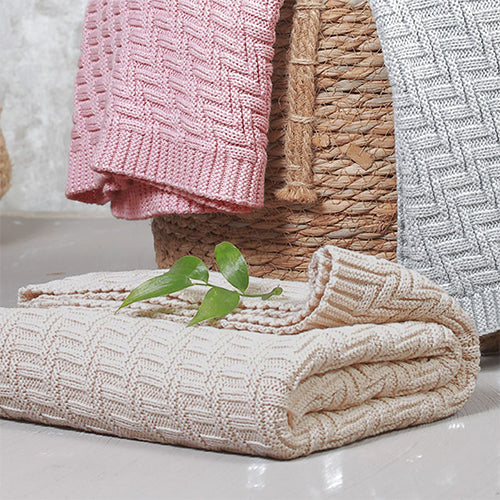 Cotton knitted blanket in beige with zigzag knit texture, folded and stacked