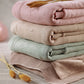 Stack of knit blankets, including a green cotton flannel-lined blanket