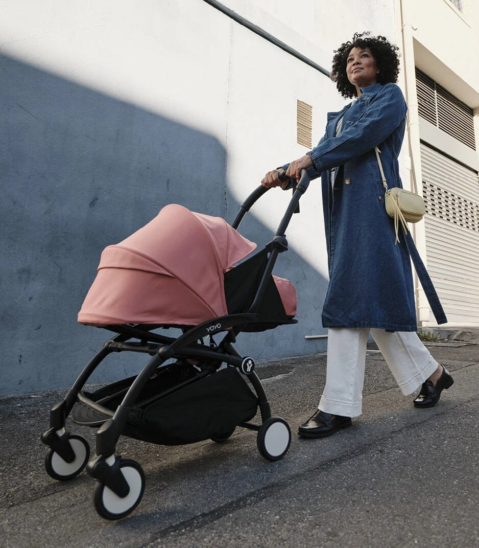 Pink newborn stroller with carrycot and seat, push handle, front wheel view
