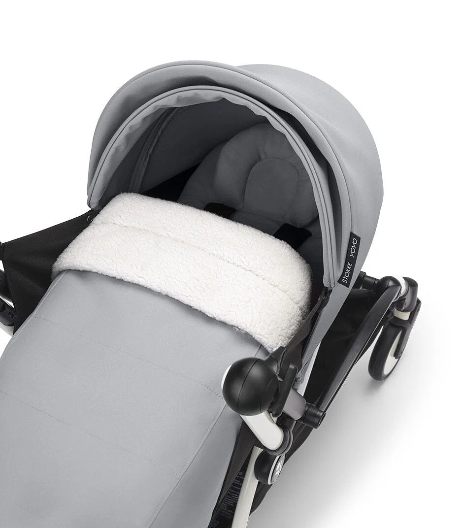 Newborn stroller seat in gray fabric with plush white insert and canopy