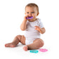 Heart-shaped teething toys: baby holding a purple ring; mint and pink pieces on floor