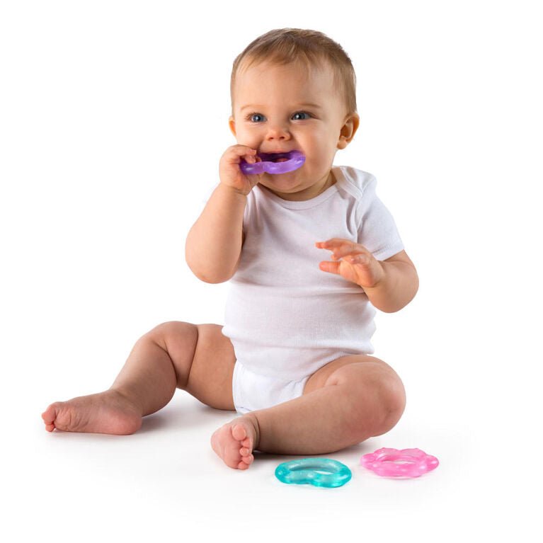 Heart-shaped teething toys: baby holding a purple ring; mint and pink pieces on floor