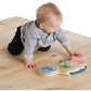 Wooden drum toy on floor with colored animal dials as baby plays