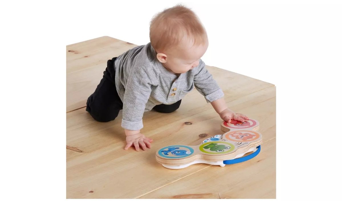 Wooden drum toy on floor with colored animal dials as baby plays