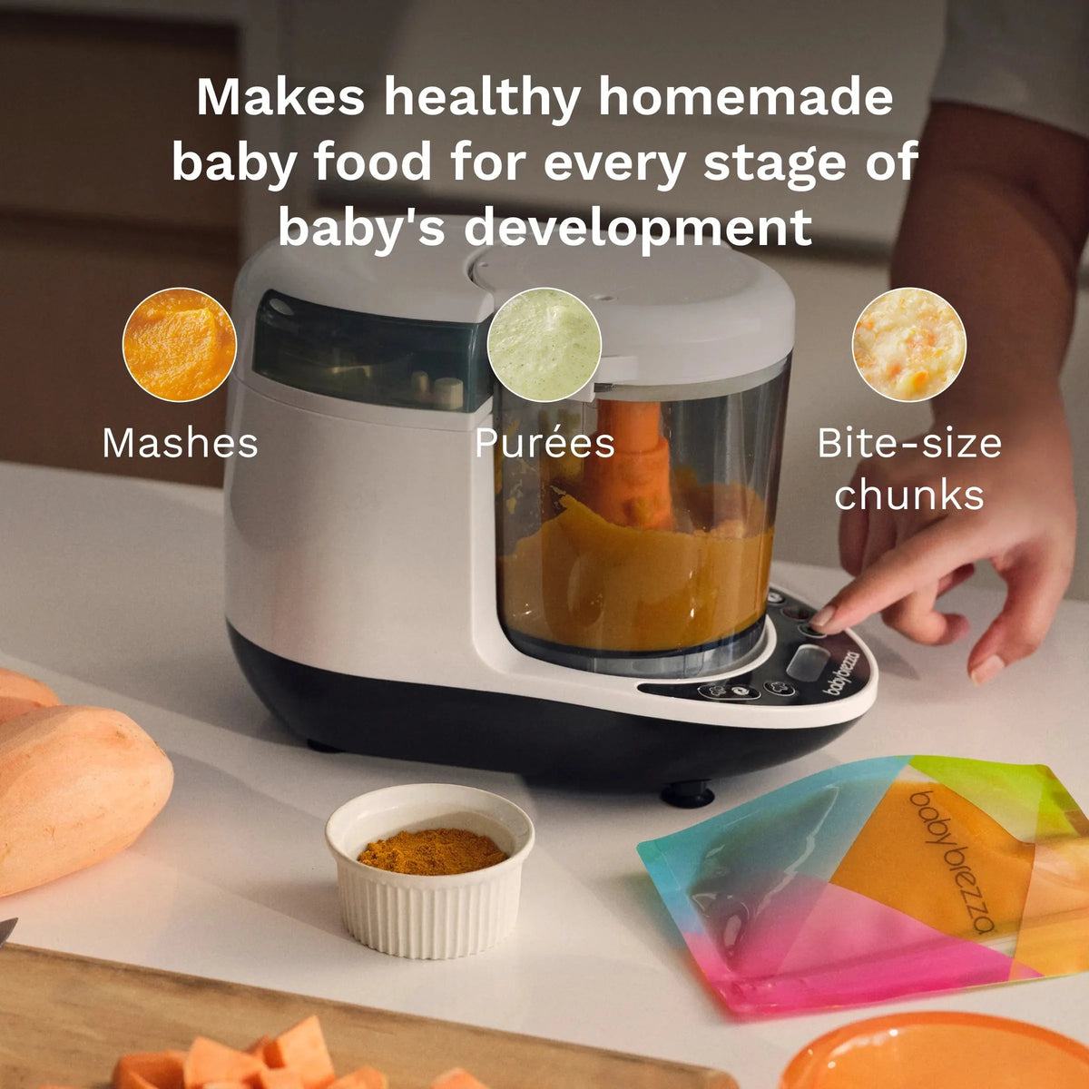 Baby food maker with blended carrot puree in jar and hand preparing food