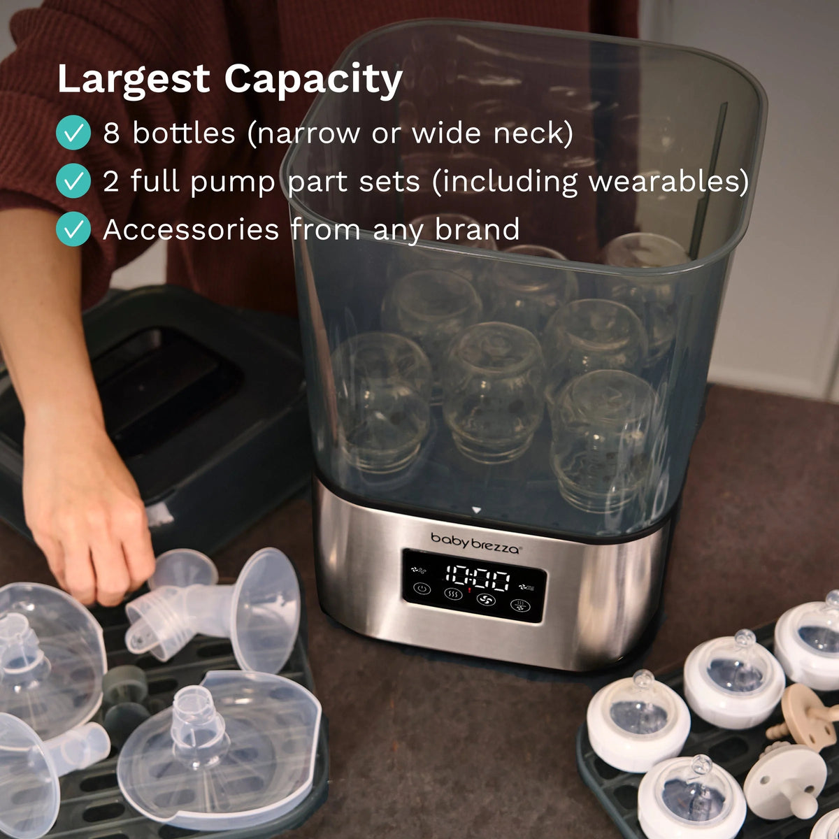 Countertop sterilizer dryer with open clear chamber filled with bottle caps and pump parts.