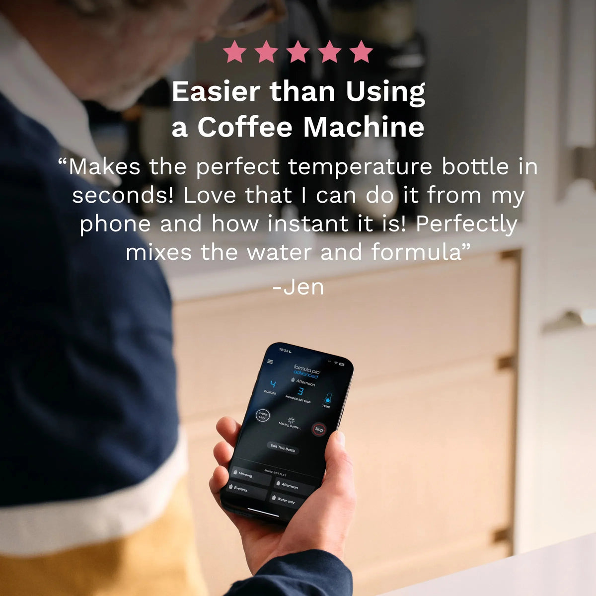 Person holding a smartphone displaying app controls for the black baby formula dispenser