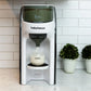 White countertop baby formula dispenser with tinted lid window, front spout, and bottle on tray