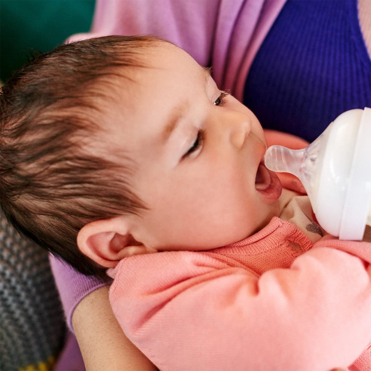 Baby drinking from a white bottle teat during feeding