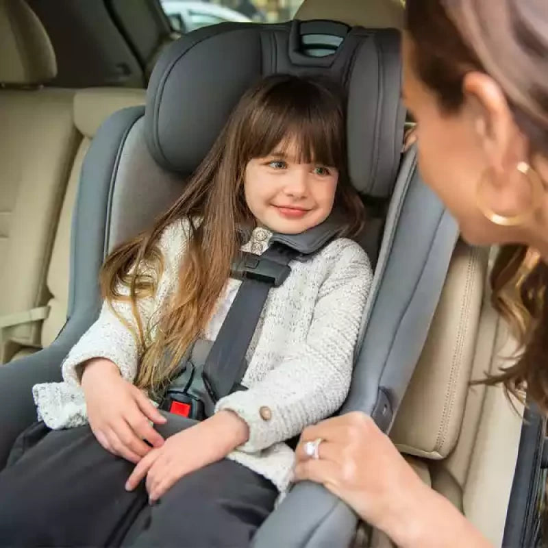 Gray Nuna car seat with child seated and five-point harness, front view
