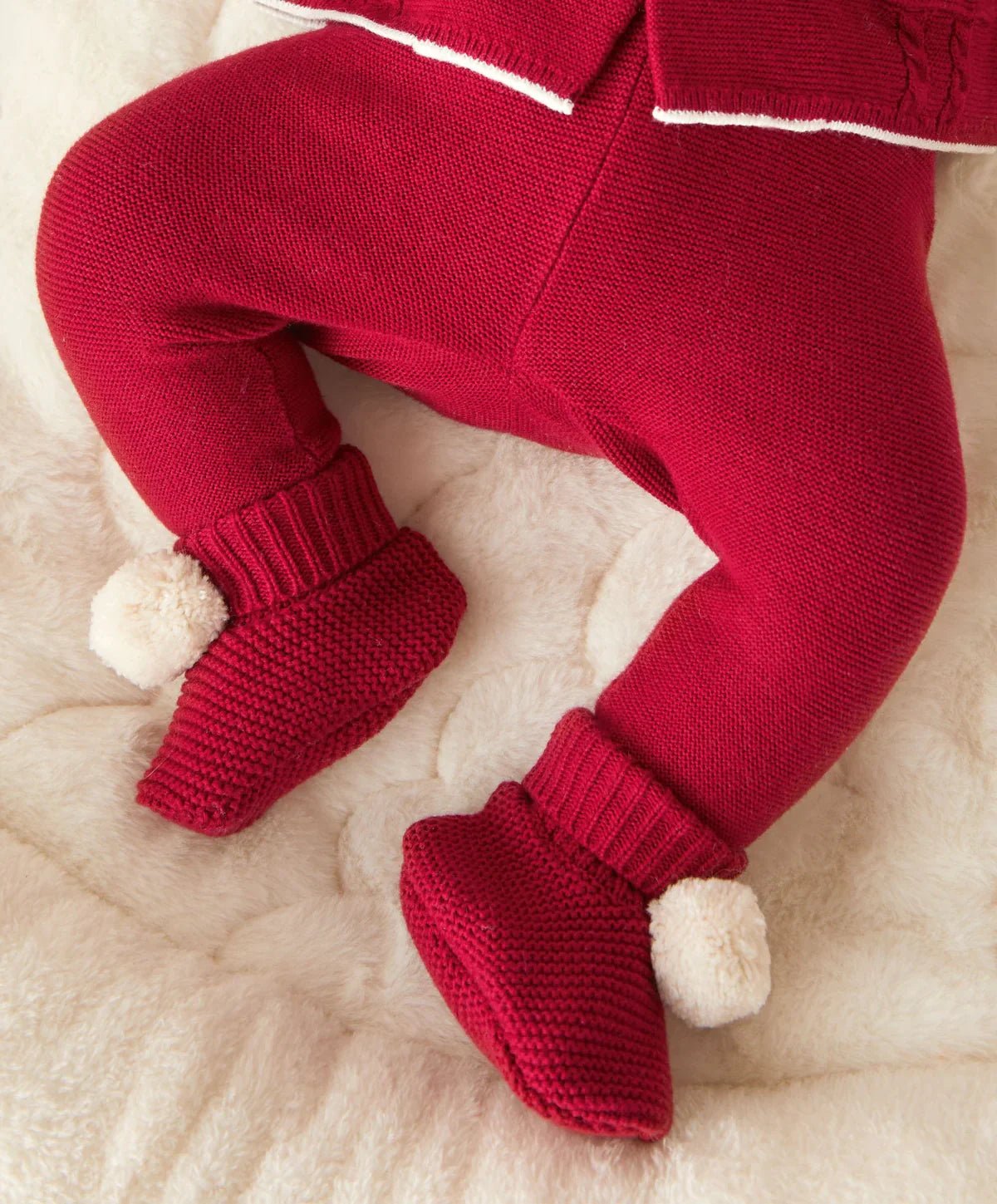 Red knit pom pom booties with ribbed cuff and fuzzy white pom-poms