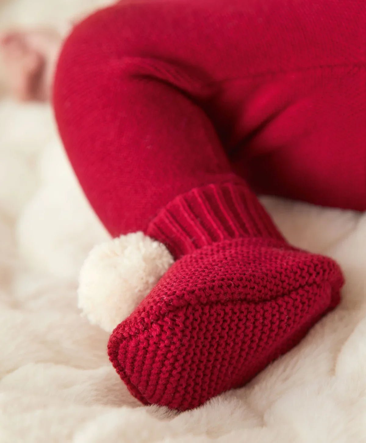 Red knit booties with cuff detail and small white pom-poms