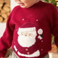 Red knit Christmas jumper close-up with Santa face and white striped hem graphic