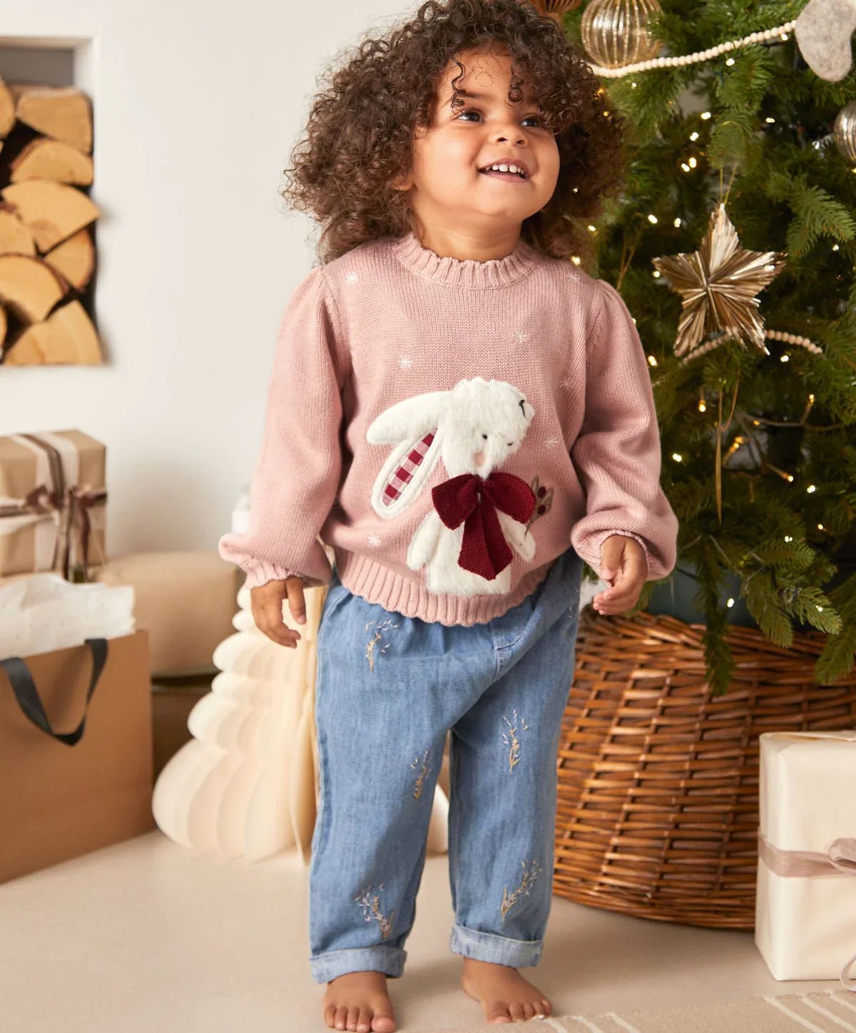 Light pink bunny Christmas sweater with long sleeves, ribbed cuffs, and front bow appliqué