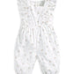 White baby dungarees with short ruffled straps and small scattered floral motifs