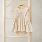 Cream mock skirt romper with ruffled shoulder straps, floral applique, and matching headband