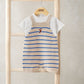 Striped knitted dungarees with blue stripes and red graphic, layered over white T-shirt