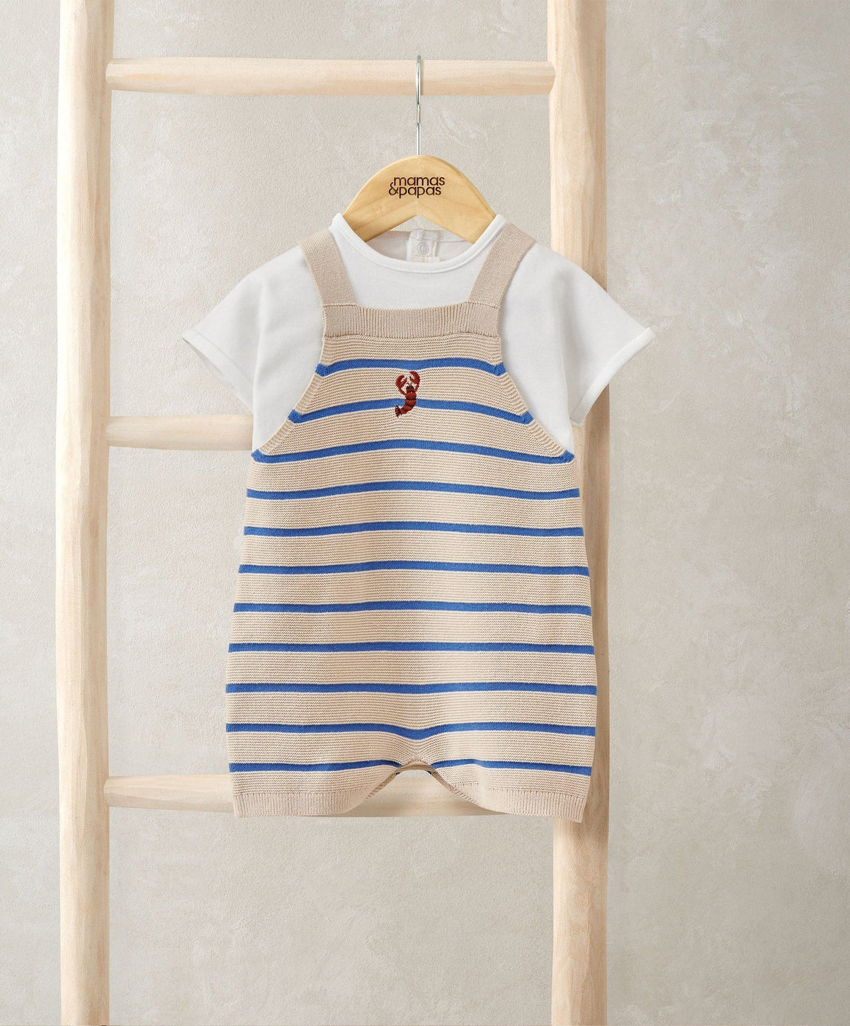 Striped knitted dungarees with blue stripes and red graphic, layered over white T-shirt