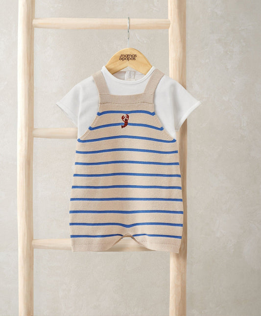 Striped knitted dungarees with blue stripes and red graphic, layered over white T-shirt