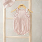 Light pink baby romper with scalloped lace trim and gathered waist; matching sun hat