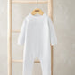 White pointelle-knit romper with long sleeves and footed legs