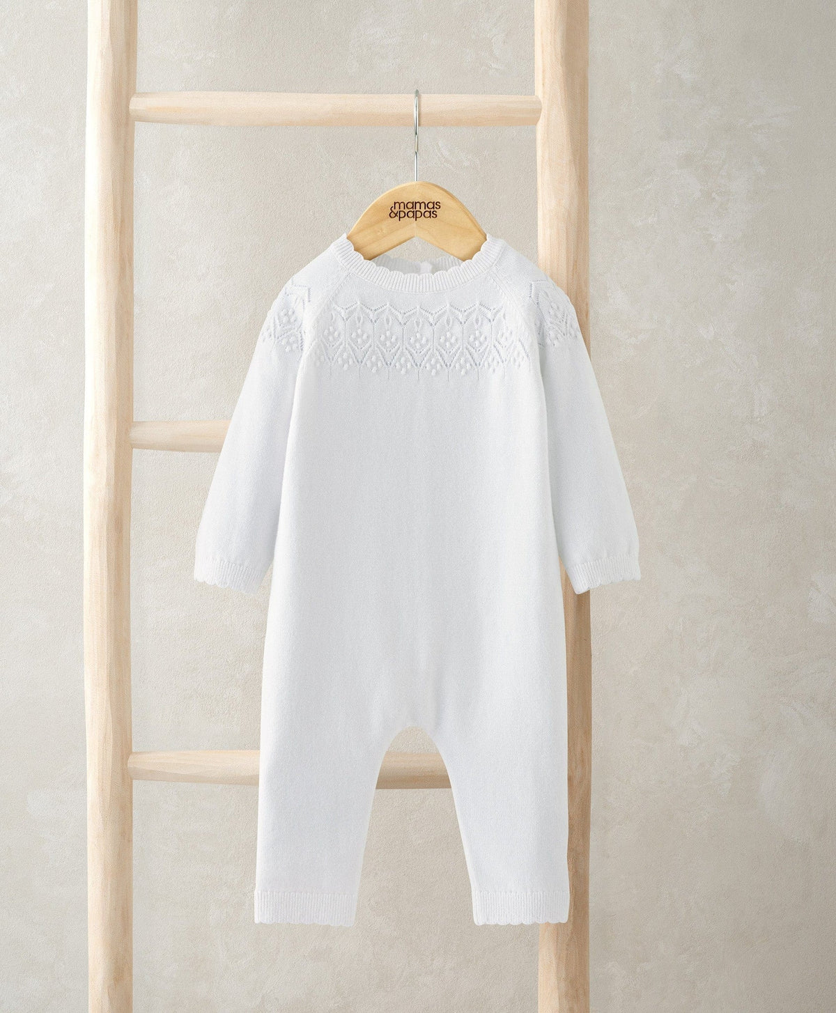 White pointelle-knit romper with long sleeves and footed legs
