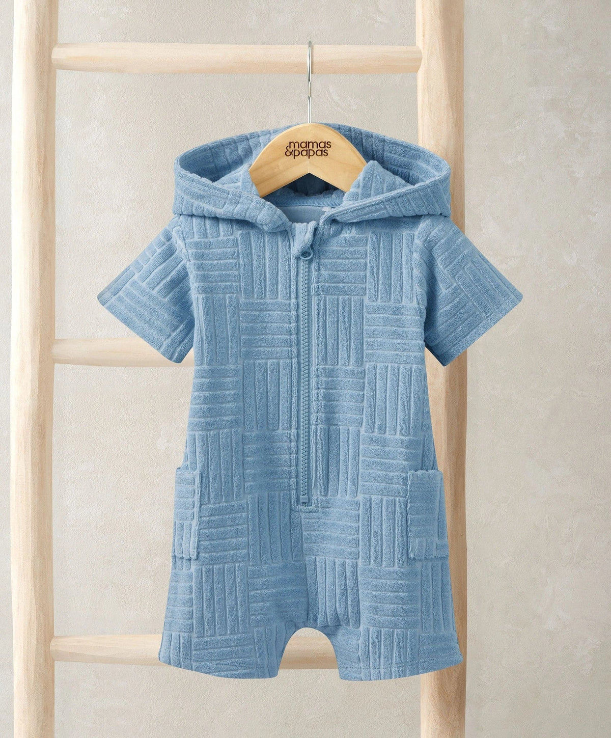 Light blue hooded towelling romper on hanger, full zip front and short sleeves, textured