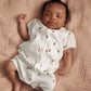 Strawberry-print short-sleeve romper worn by a sleeping baby, button front