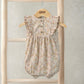 Ditsy floral shortie romper with ruffled cap sleeves and button front on cream fabric