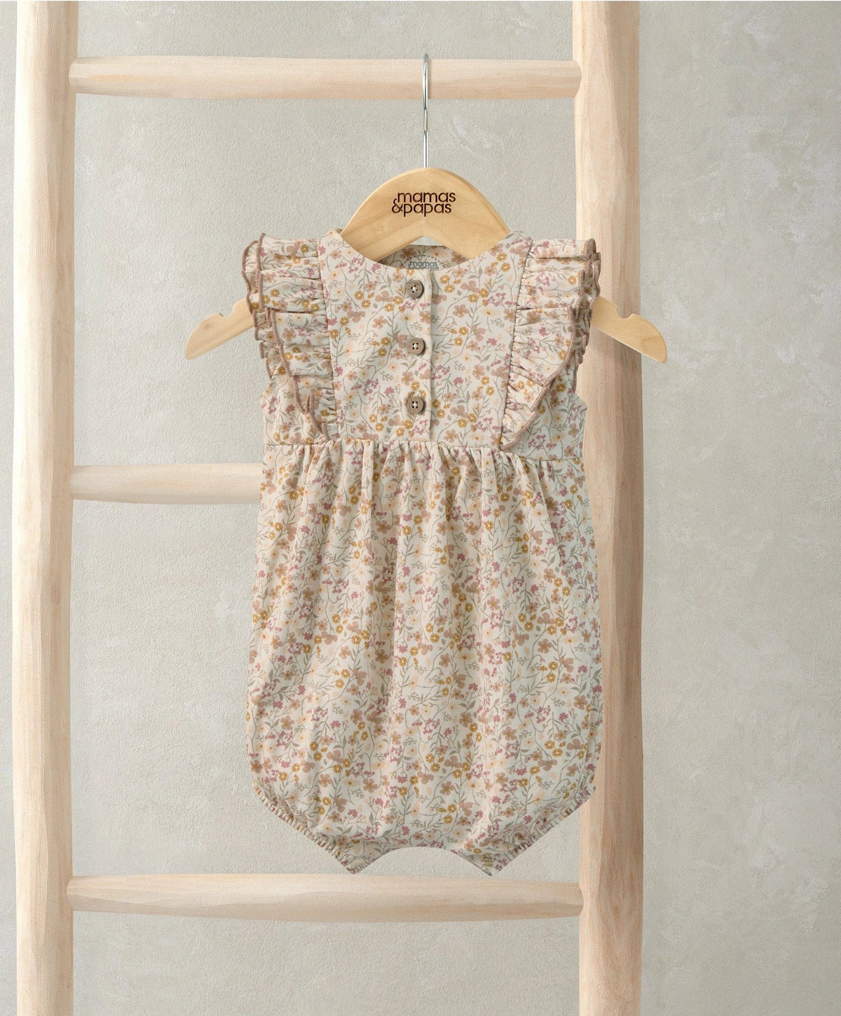 Ditsy floral shortie romper with ruffled cap sleeves and button front on cream fabric