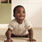 Ribbed baby romper in cream with small animal print, short sleeves and button placket