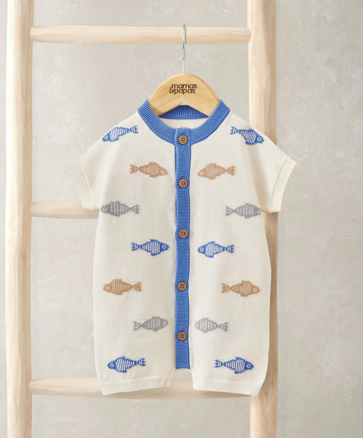 Cream knitted romper hanging, blue button front, fish pattern, short sleeves, ribbed hem