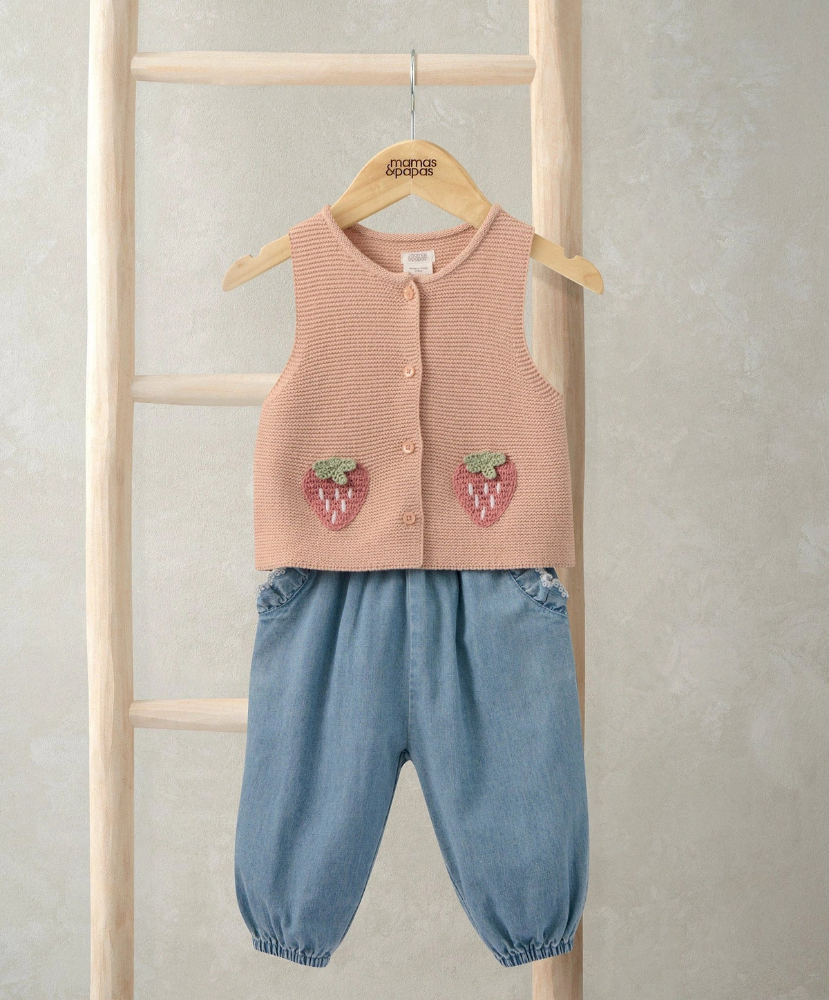 Pink knitted waistcoat with button front and strawberry appliques; denim trousers